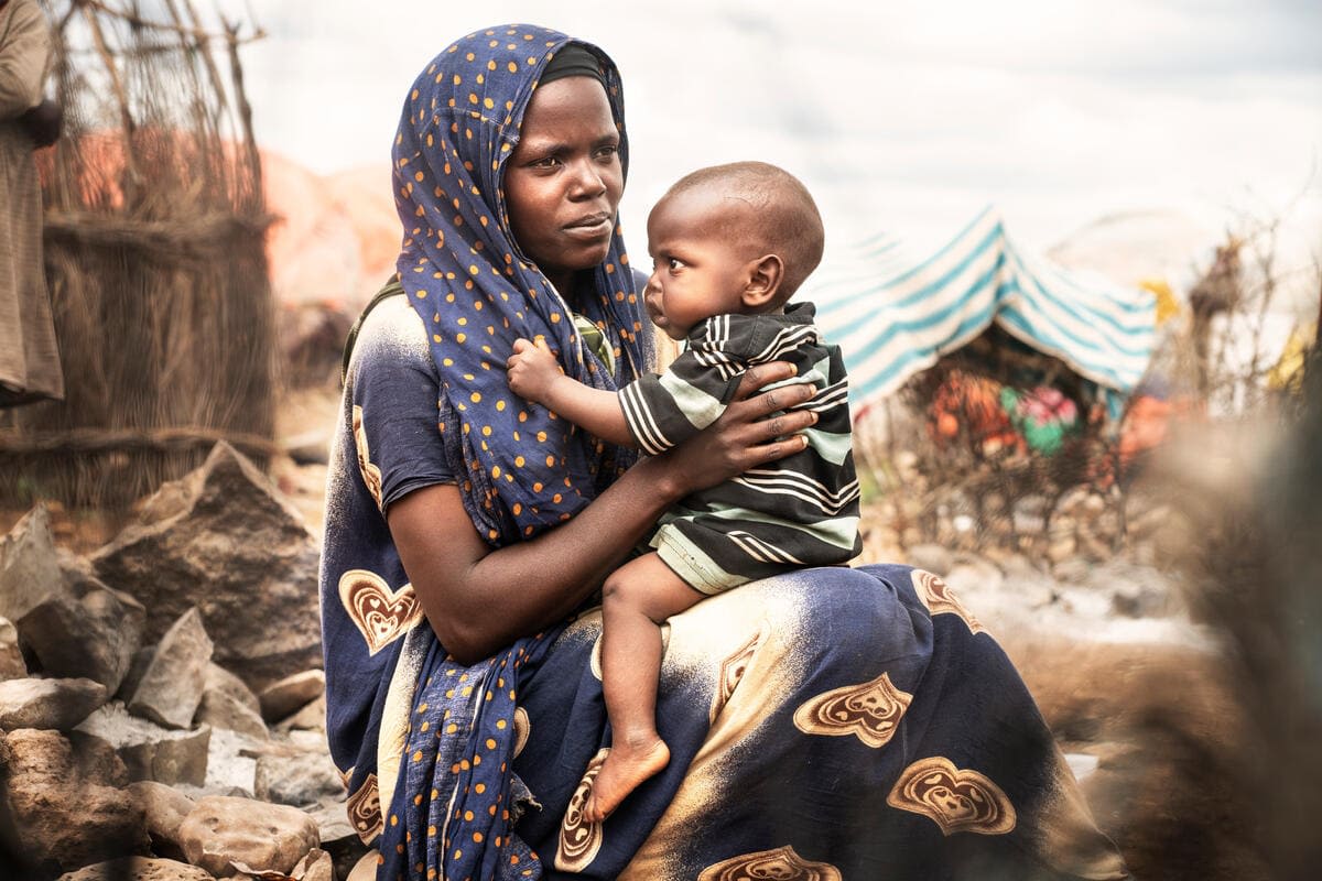 Mamma e bambino di pochi anni seduti a terra nel Corno d'Africa